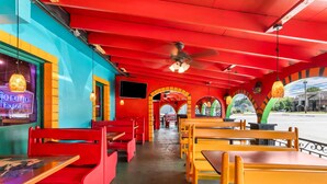 Un restaurant amb seients vermells i grocs, un ventilador de sostre i un cartell de neó.