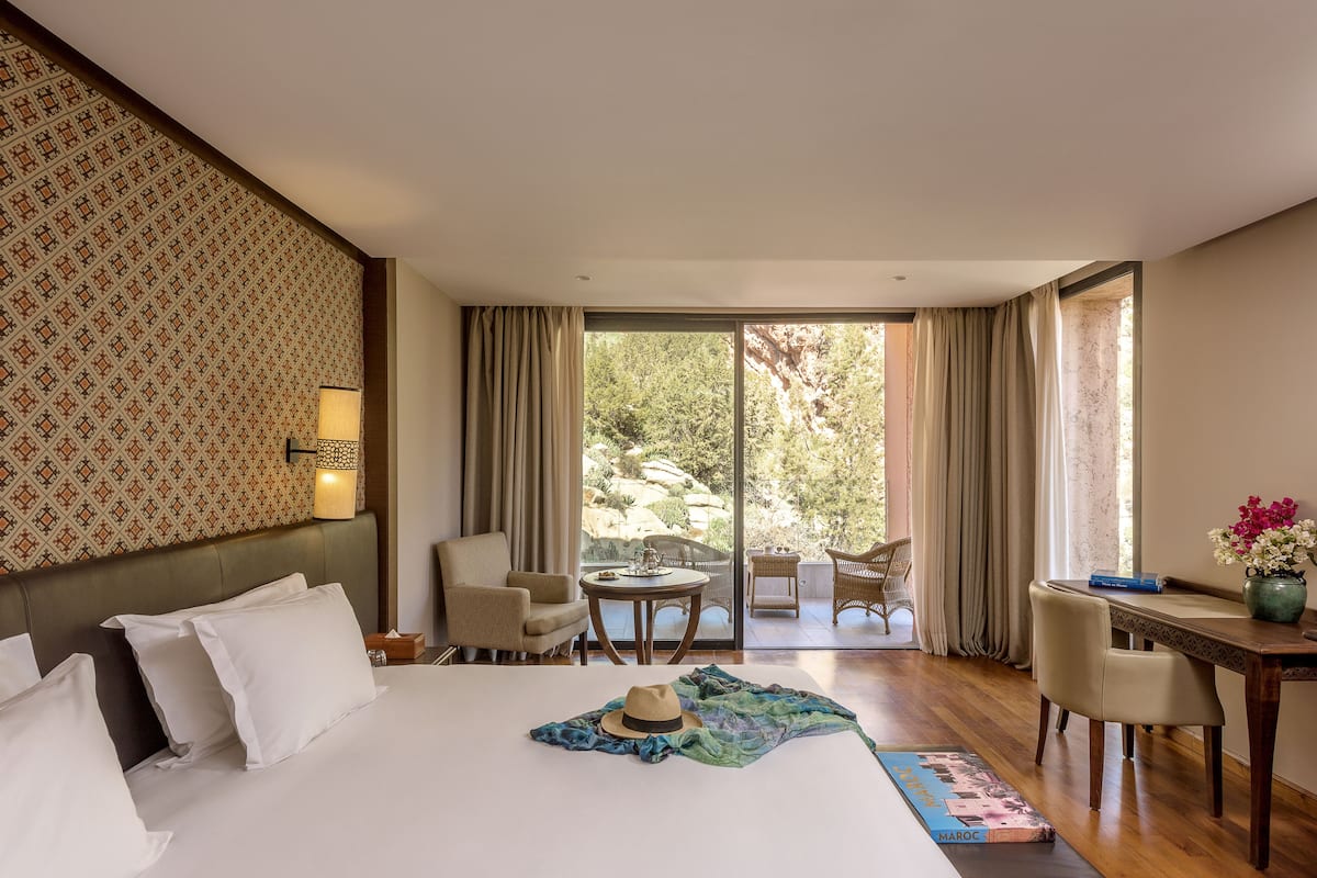 Una habitación de hotel con una cama grande, una mesa de comedor, una silla y vistas al exterior.