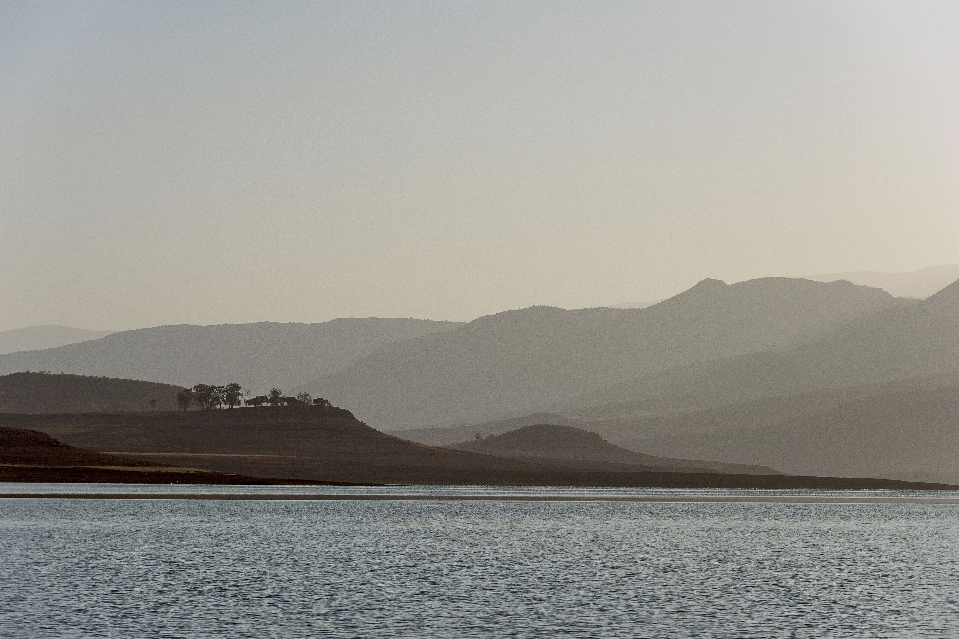 A calm lake with distant mountains and a clear sky.
