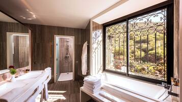 A modern bathroom with a large window, a shower, and a bench with towels.