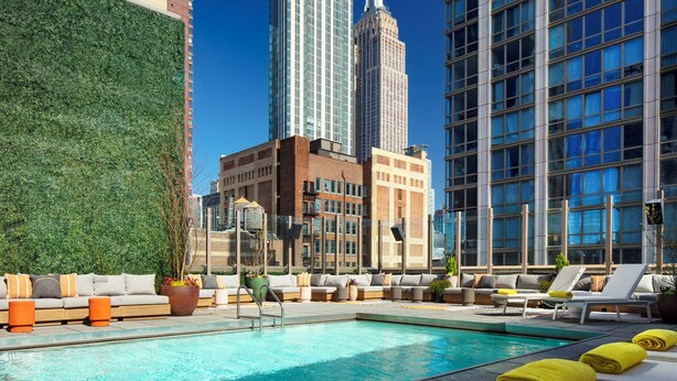 Zona de piscina al terrat amb gandules, una paret vegetal i vista de l'Empire State Building.