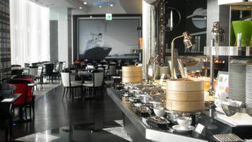 A modern restaurant interior with a buffet setup, dining tables, and chairs.