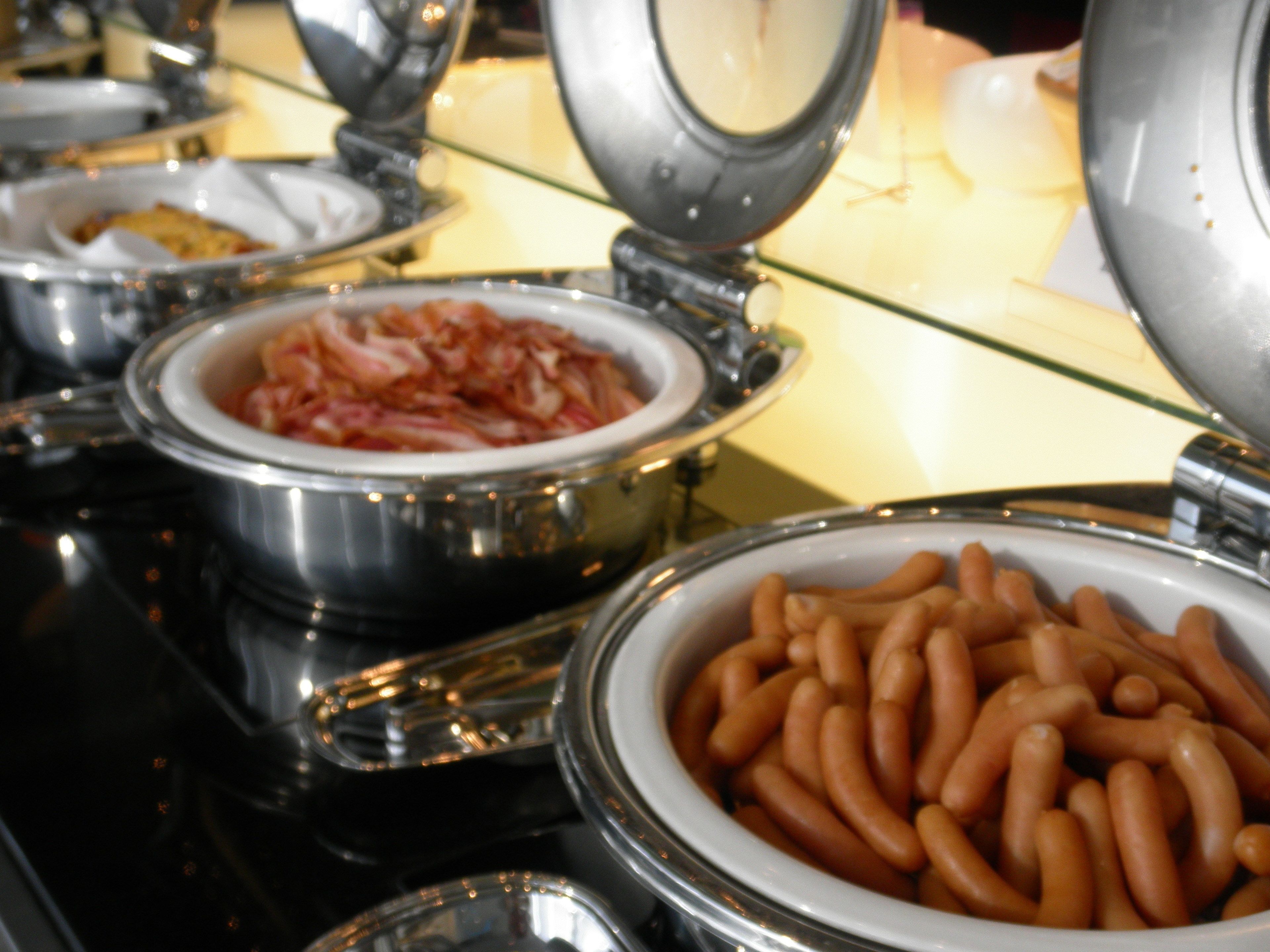 Ein Buffet mit verschiedenen Speisen, darunter eine Schüssel Wurst und eine Schüssel, die wie ein Gericht mit Fleisch aussehen.