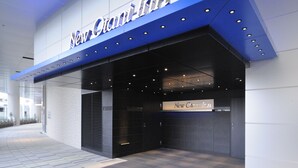 El exterior del New Century Inn, con un diseño moderno, que destaca una entrada y señalización prominentes.
