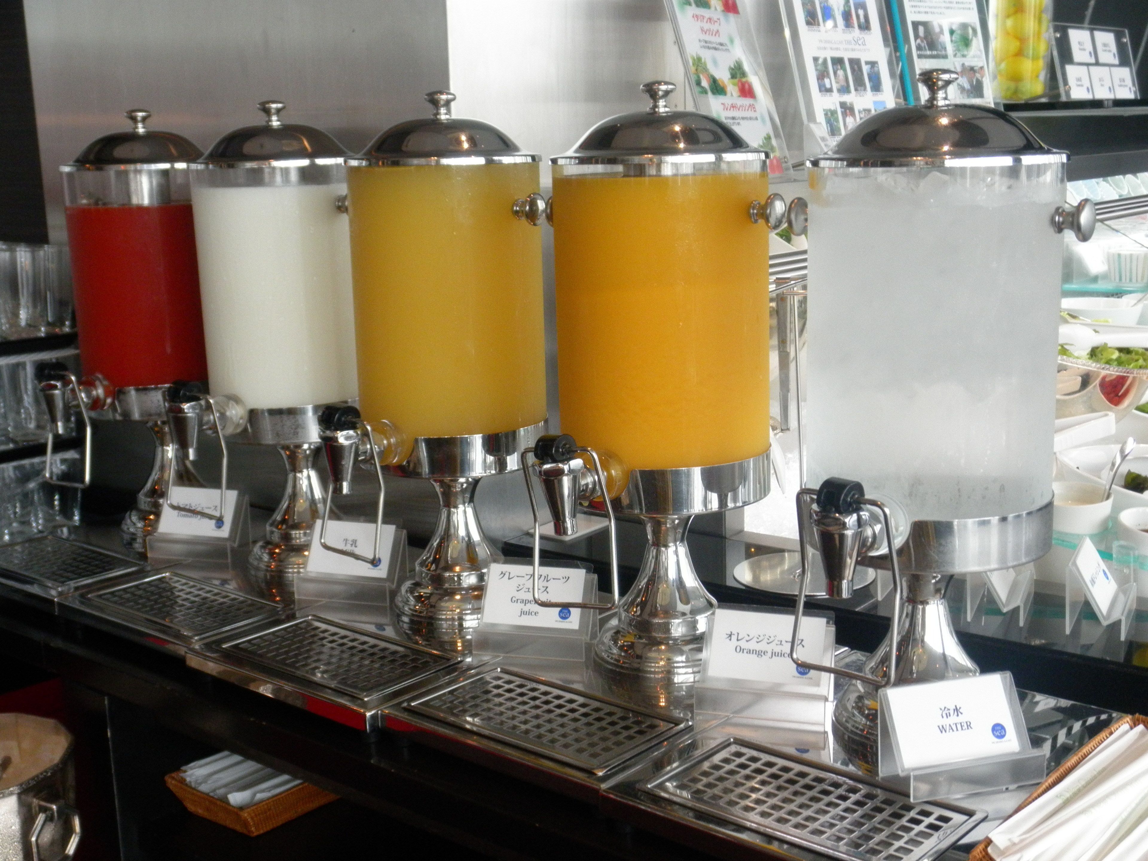 Dispensador de bebidas com várias opções, incluindo suco de laranja.