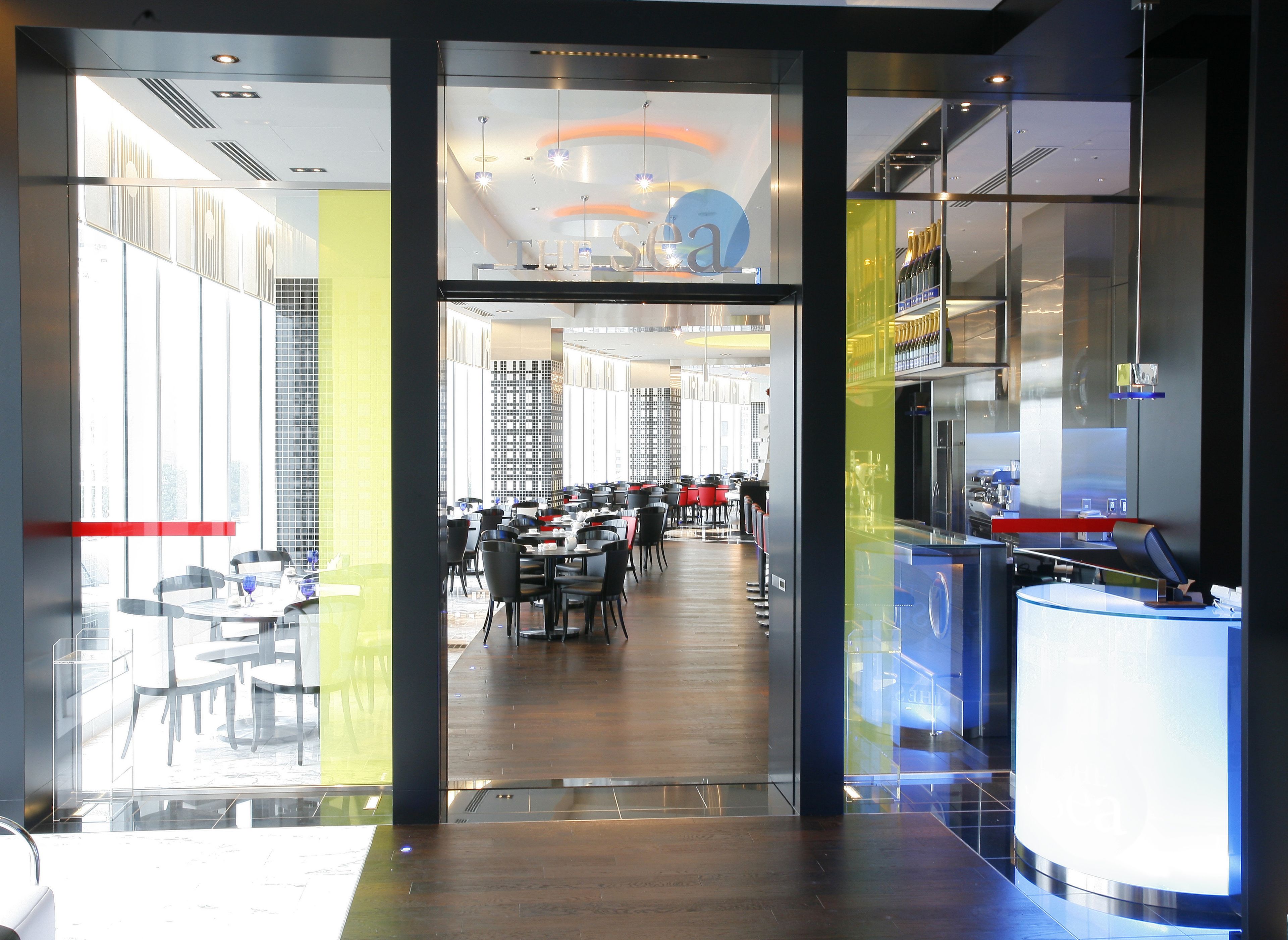 Ein modernes Restaurant mit Glastür, mehreren Tischen und einer Bar.