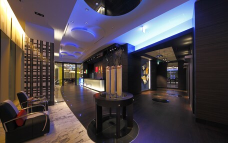 A modern lobby with a reception desk, seating area, and a decorative column.