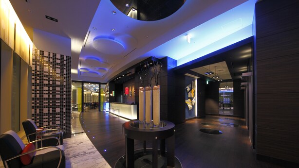 Un vestíbulo moderno con mostrador de recepción, zona de estar y una columna decorativa.
