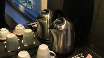 Ein ordentlich angelegter Kaffee-Bereich mit verschiedenen Tassen, einem Wasserkocher und Teekannen auf einem Tisch.