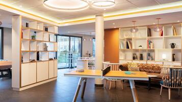 Un interior moderno con una mesa central, sillas y un sofá. Hay estanterías a ambos lados de la habitación.