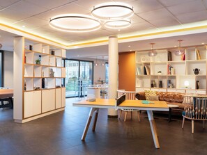 Un interior moderno con una mesa central, sillas y un sofá. Hay estanterías a ambos lados de la habitación.