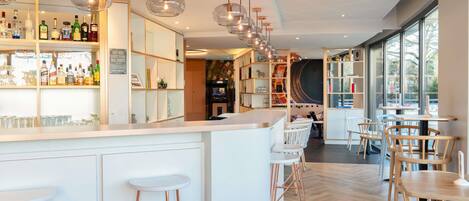 A modern bar area with a white counter, copper bar stools, and pendant lighting.