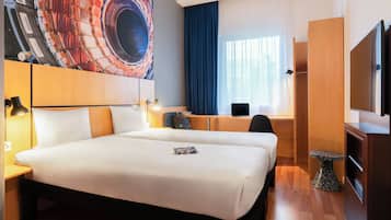Ein Hotelzimmer mit einem großen Bett, einem Schreibtisch mit Computer, einem Fernseher und einem Gemälde an der Wand.