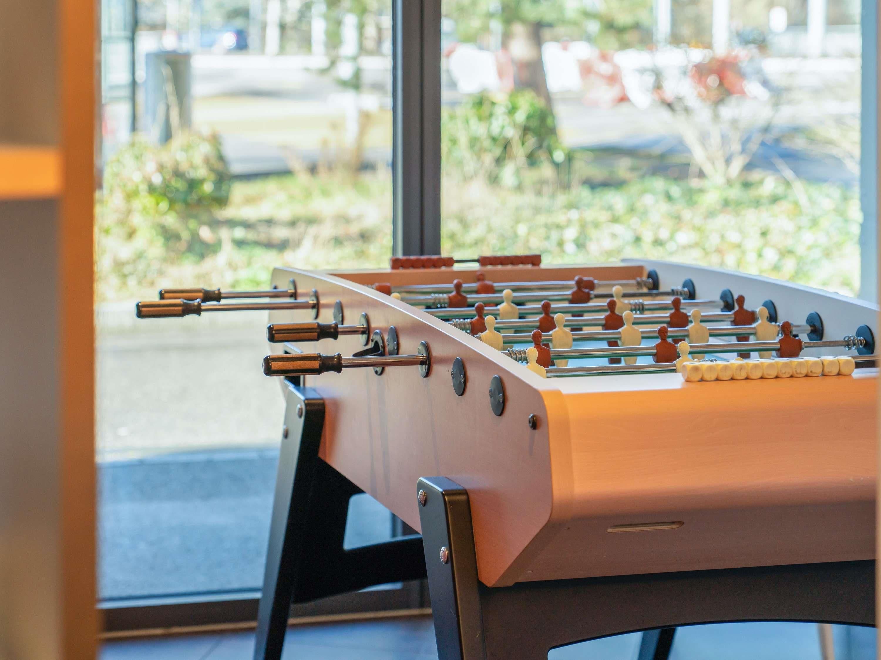 Une table de baby-foot dans une pièce avec une grande fenêtre.