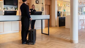 A modern hotel lobby with a reception desk, a bar area, and a clock on the wall. - ibis Geneve Petit Lancy (Lancy)