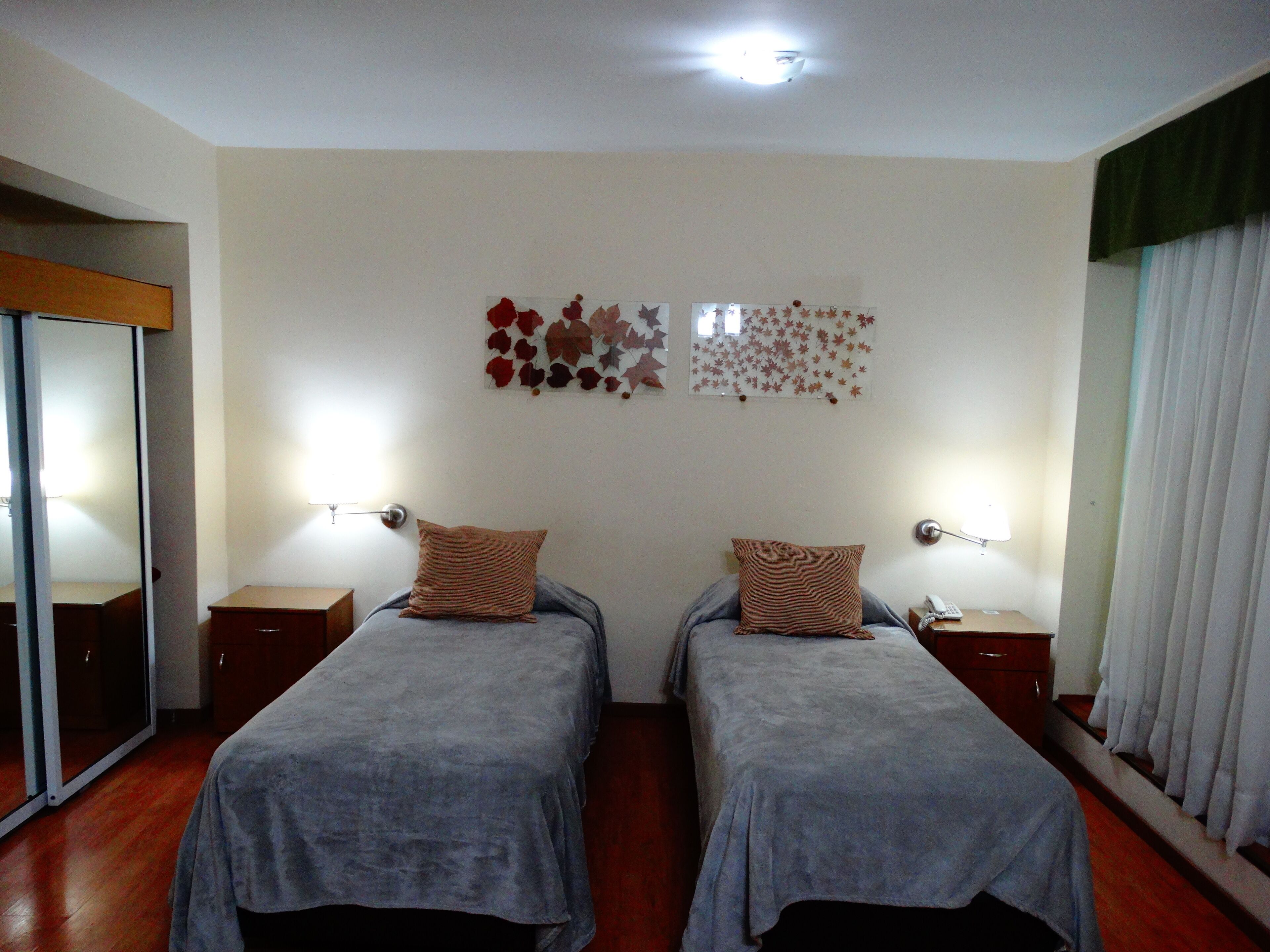 A twin room with two beds, a sliding door, and a mirror.