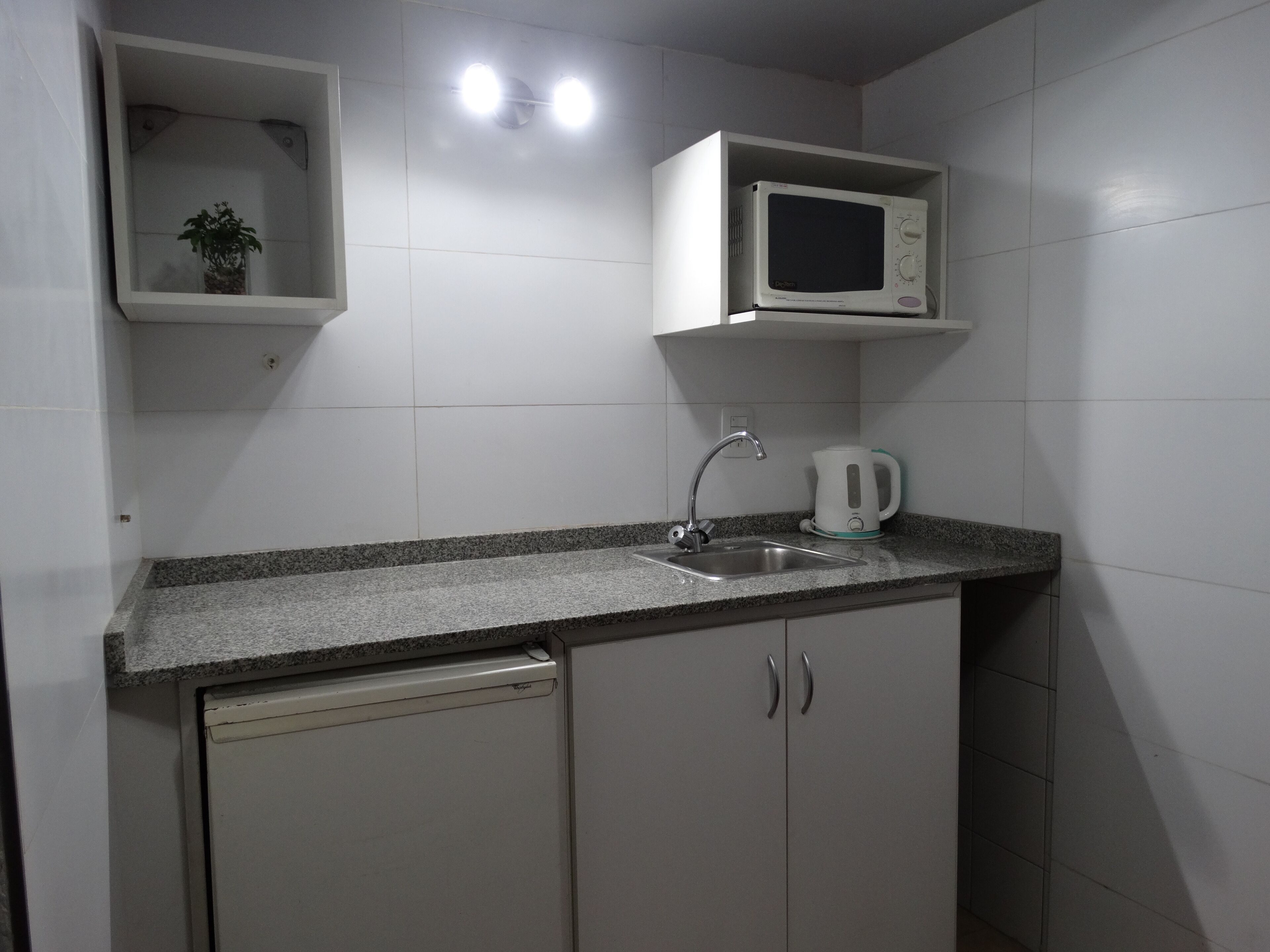 A compact kitchen with a built-in microwave, a kettle, and a dishwasher.
