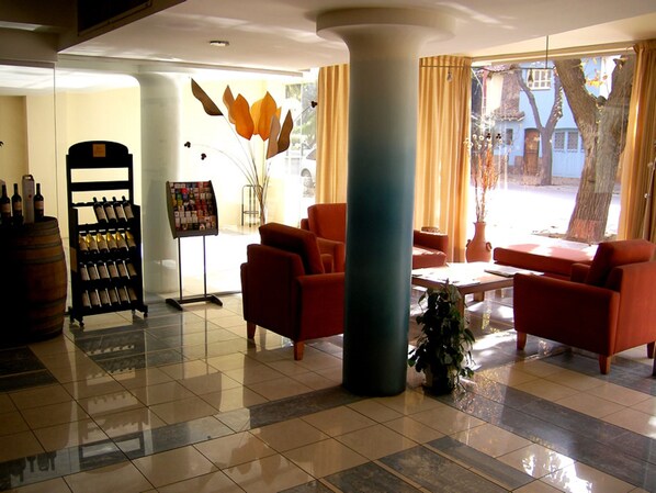 A lobby with a wine rack, seating area, and a large pillar. - Apart Hotel San Lorenzo (Mendoza)