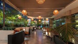 Un espace intérieur moderne doté de coins salon, d’un éclairage d’ambiance et de grandes fenêtres offrant une vue sur la verdure.