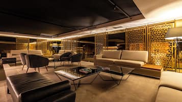 Una sala de estar moderna con un sofá, sillas, una mesa de centro y paneles decorativos.