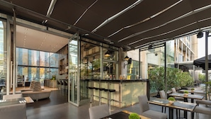 Un restaurant moderne doté d’un bar, de tables et de grandes fenêtres offrant une vue sur la ville.