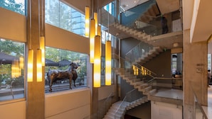 Un intérieur moderne avec un escalier en verre, une sculpture et un éclairage chaleureux.