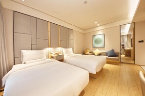 Habitació d'hotel amb dos llits, una tauleta de nit amb una làmpada, un mirall i una finestra gran.