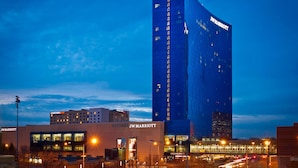 A JW Marriott hotel with a modern design, featuring a prominent vertical structure and a flat-roofed building with illuminated signage. - JW Marriott Indianapolis (Indianapolis)