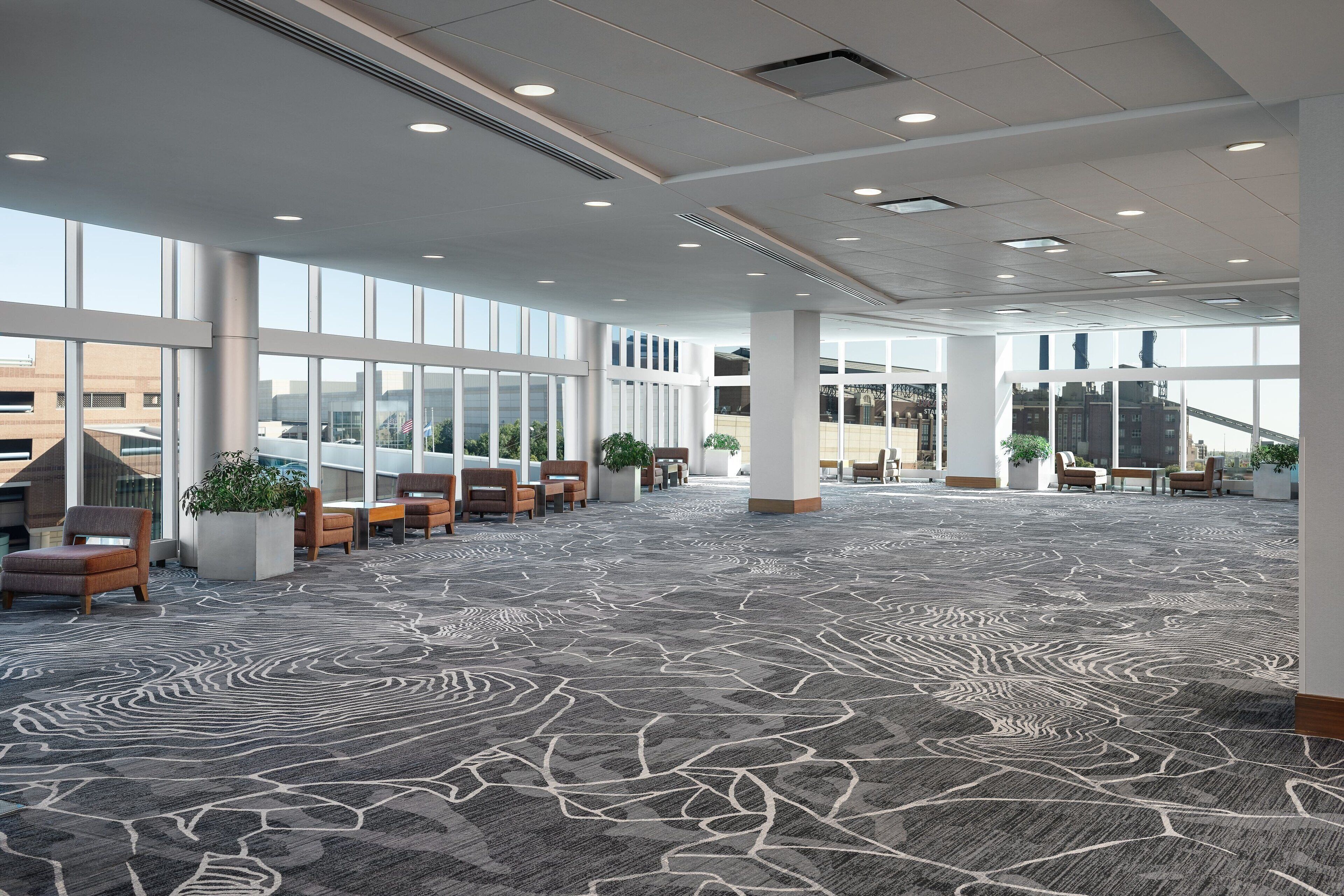A spacious lobby with a patterned carpet, seating areas, and large windows offering views of the city.