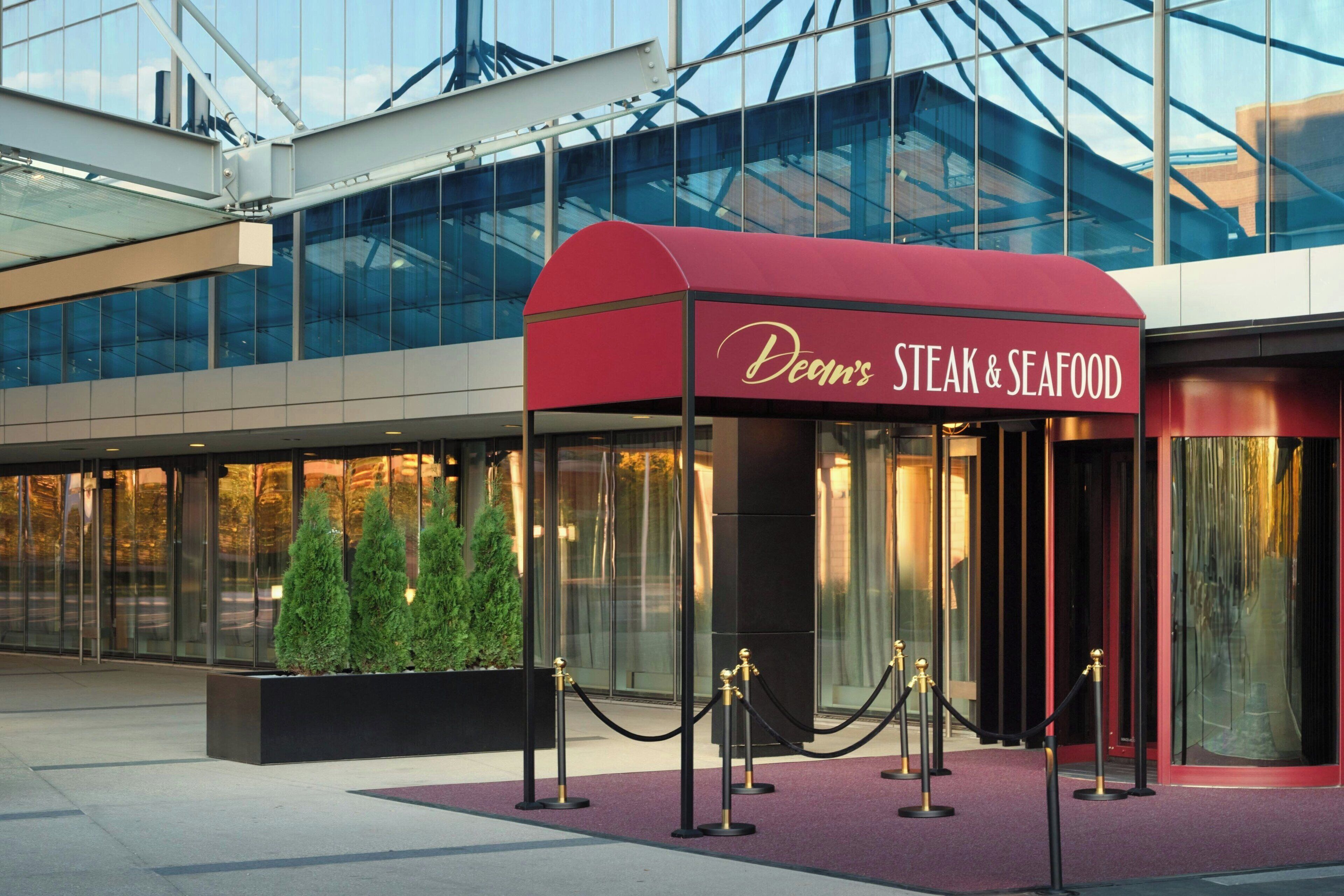 A modern building with a red awning labeled "Dean's Steak & Seafood."