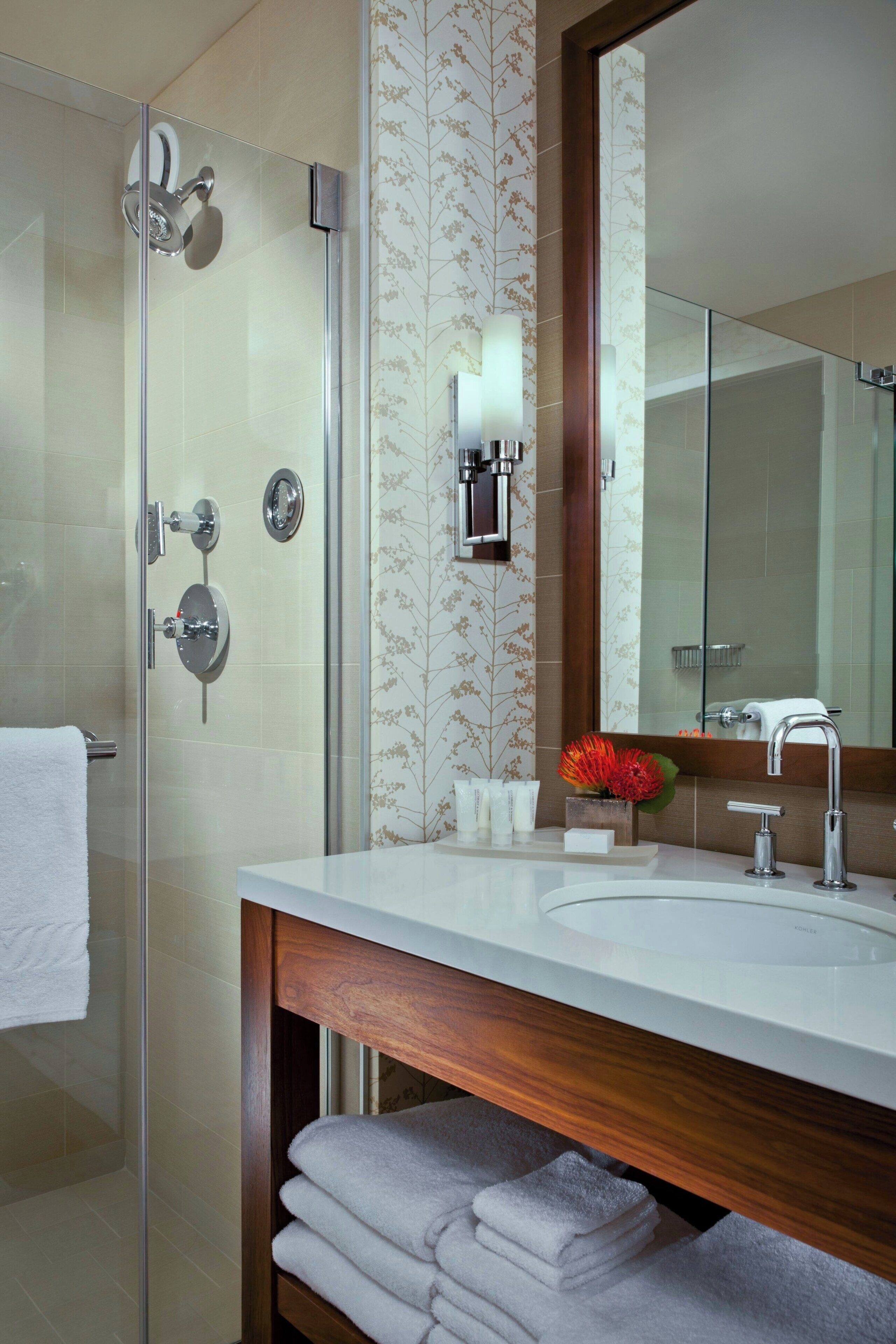 A modern bathroom with a glass shower enclosure, a wooden vanity, and a large mirror.