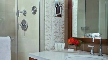 A modern bathroom with a glass shower enclosure, a wooden vanity, and a large mirror.