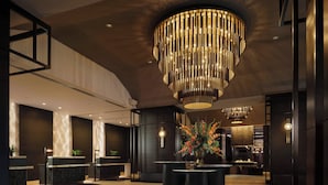 A modern lobby with a central reception desk, a large chandelier, and a seating area with a decorative centerpiece. - JW Marriott Indianapolis (Indianapolis)