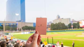 Eine Hand hält eine JW Marriott Karte, im Hintergrund ein Baseballstadion.