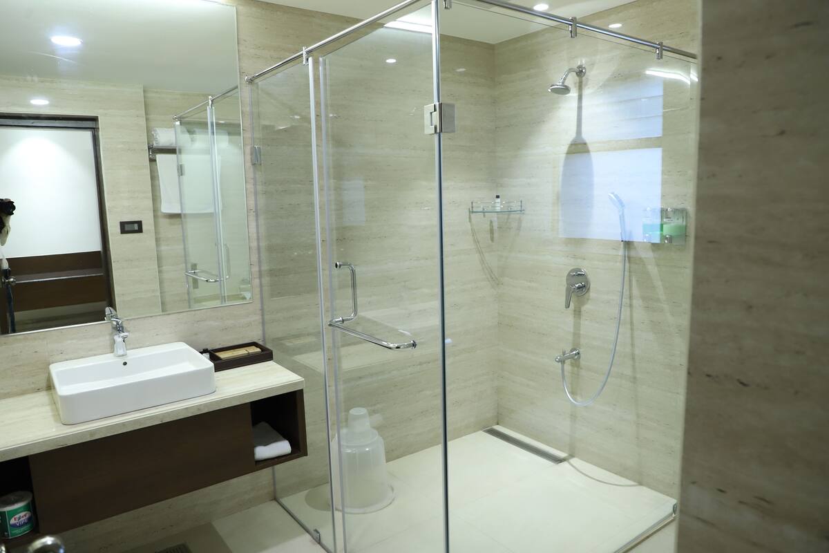 A modern bathroom with a glass-enclosed shower, a white sink, and a mirror.