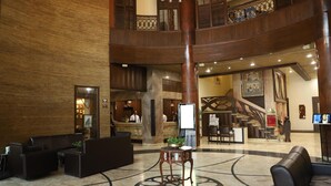 Un vestíbulo amplio con mostrador de recepción, zona de estar y una escalera que conduce a un nivel superior.