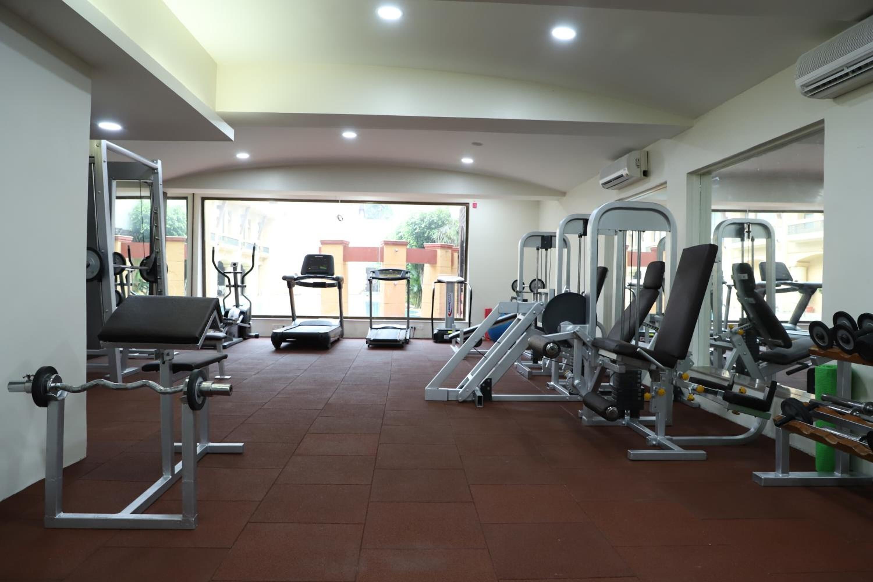 Una palestra con diverse attrezzature per l'allenamento, tra cui tapis roulant, macchinari per pesi e pesi liberi.