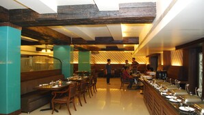 Un restaurante con vigas de madera, paredes color turquesa y un sistema de buffet.