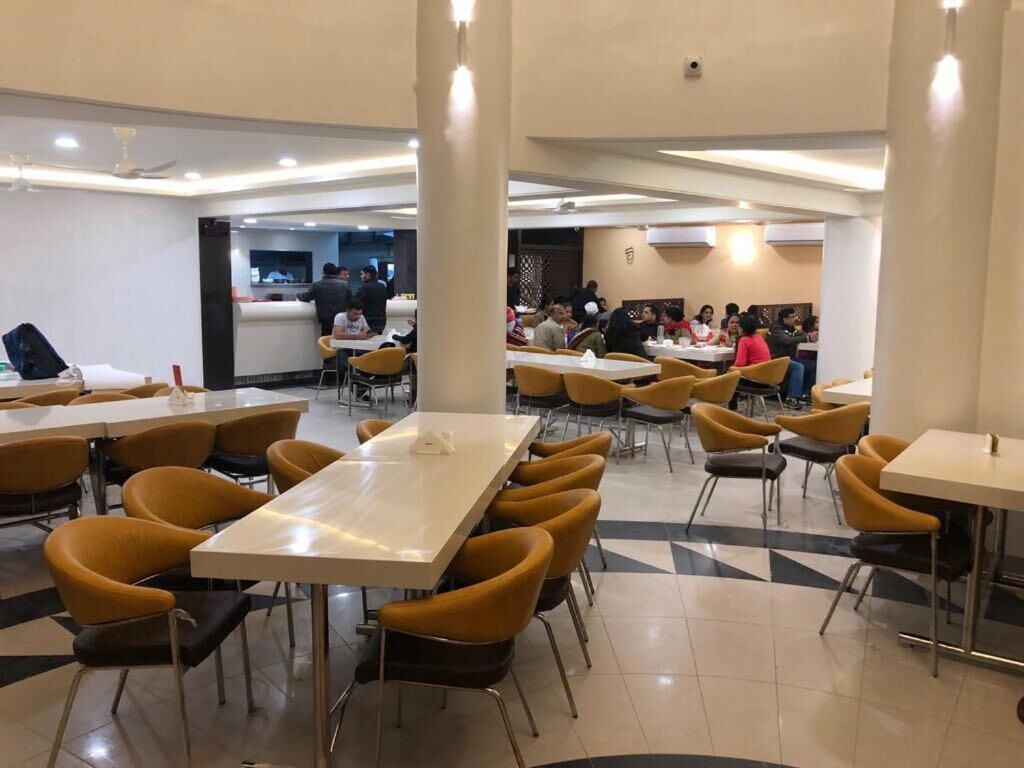 Un amplio comedor con varias mesas y sillas, una barra central y un diseño de interiores moderno.