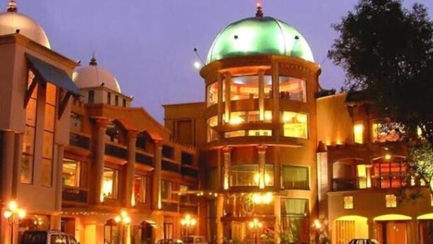 Un hotel de varios pisos, una cúpula central y un patio con coches.