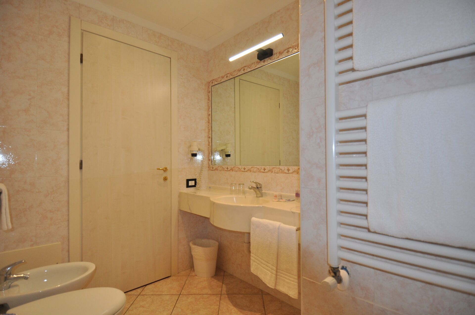 A bathroom with a double sink, a toilet, a mirror, and a towel rack.