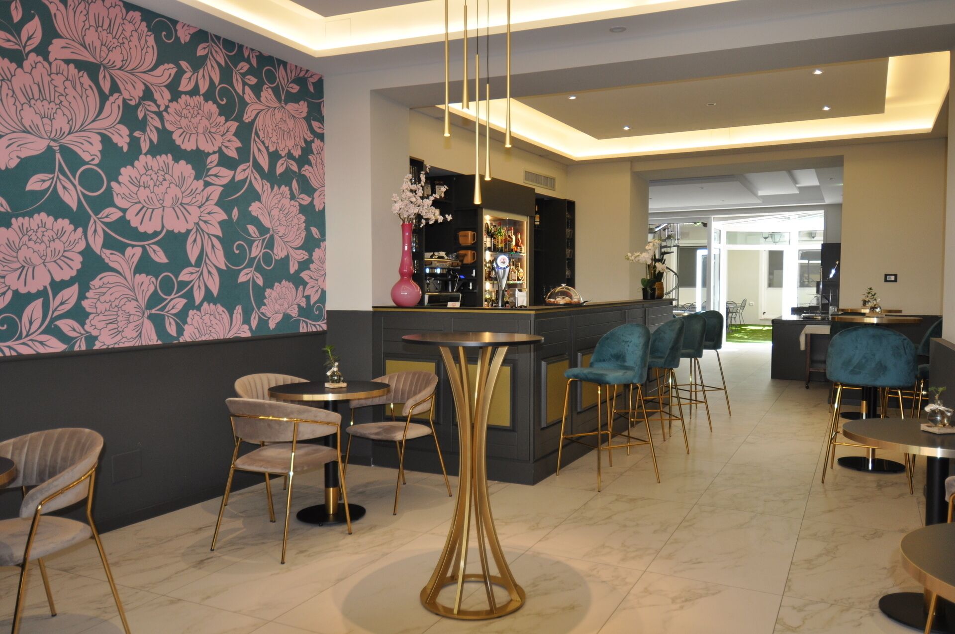 A modern bar area with a floral wallpaper, bar stools, and a bar counter.