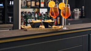 A bar area with two glasses of a red beverage, garnished with orange slices, and a tray of snacks. - Cavour 30TRE - Hotel Moderno (Stresa)