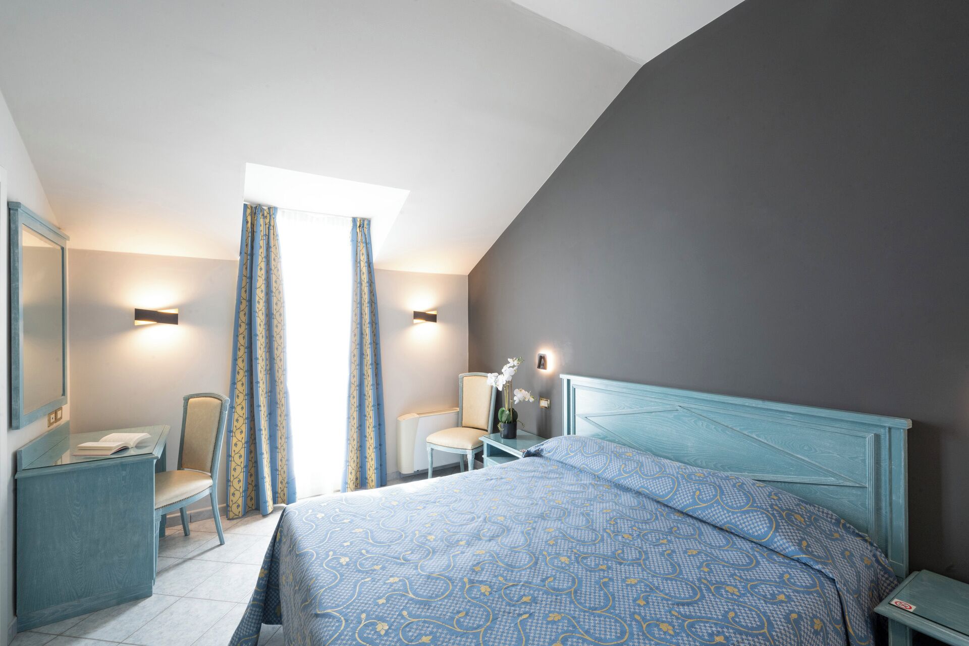 A bedroom with a bed, a desk, a chair, and a nightstand.