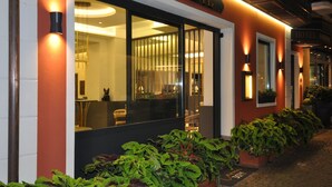 A restaurant with a modern facade, large windows, and outdoor plants. - Cavour 30TRE - Hotel Moderno (Stresa)