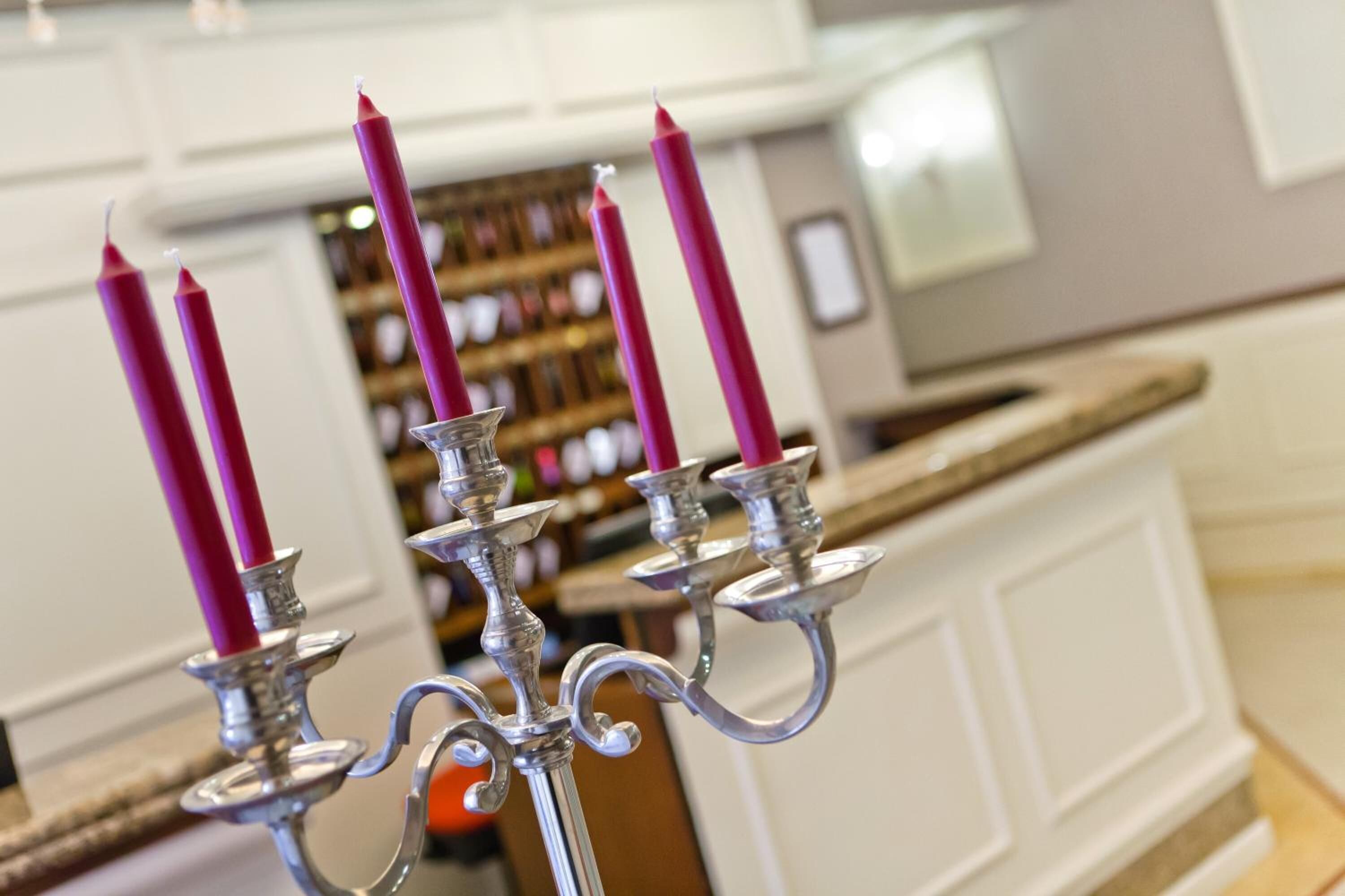 Un candelabro con velas rosas en una habitación bien iluminada, con paredes blancas y una encimera de madera.