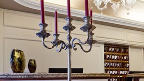 Een glazen tafel met een kandelaar, een decoratief kussen en een wijnrek op de achtergrond.