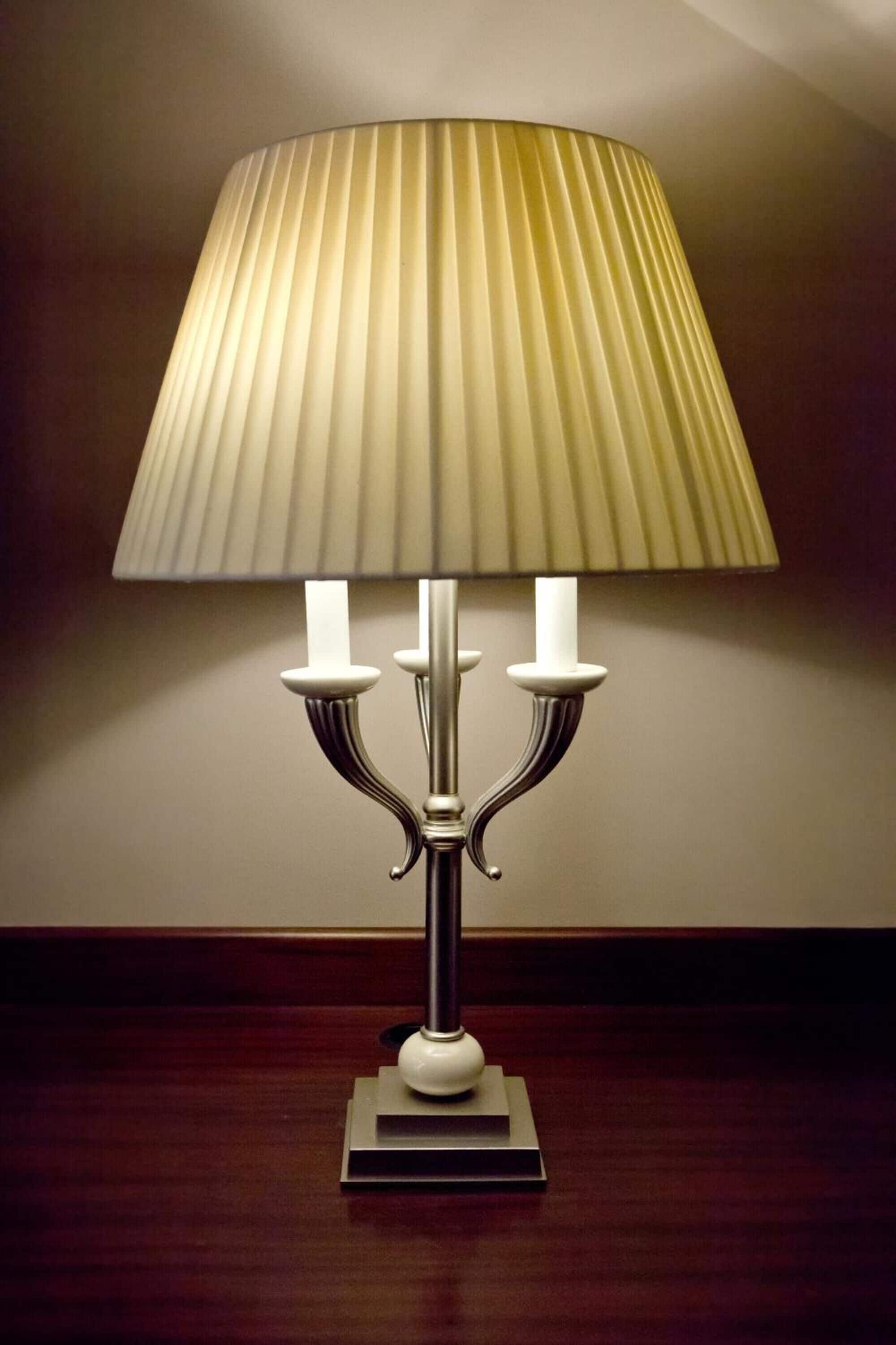 A table lamp with a pleated shade and three candle-like holders.