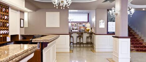 A spacious kitchen with a marble countertop, a chandelier, and a bar area with stools.