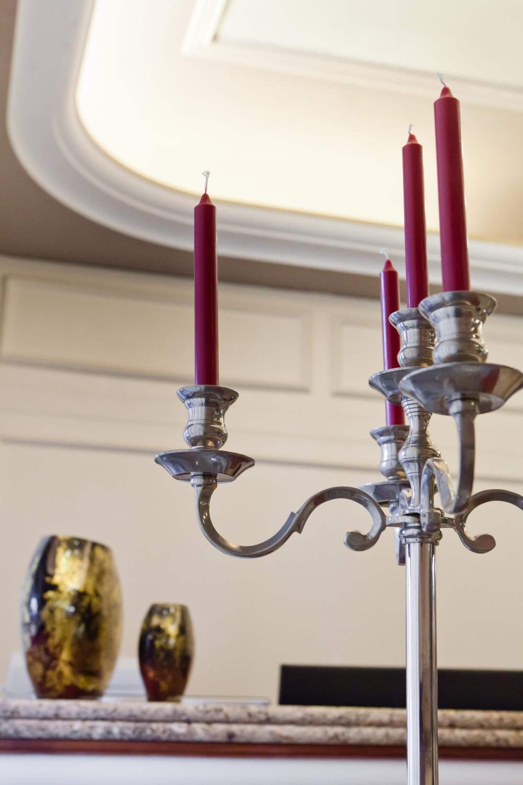 A candelabra with three red candles, a decorative glass object, and a fireplace mantel.